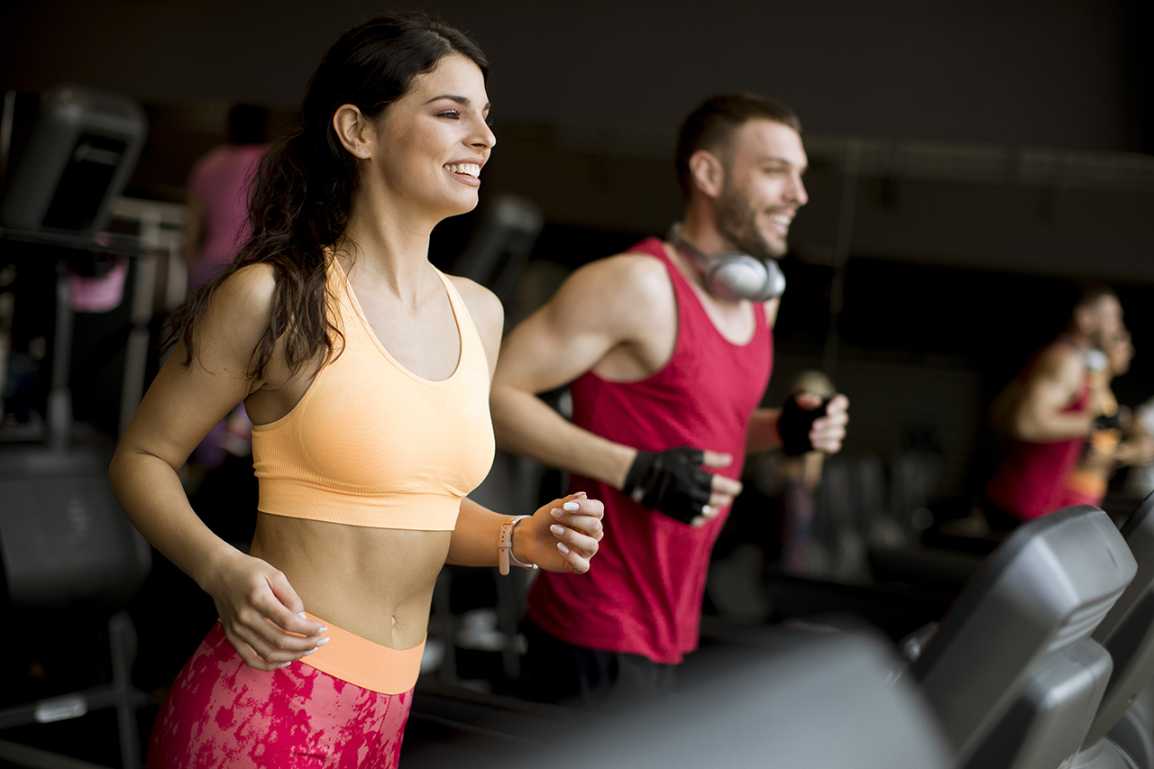 Young couple running on treadmills in modern gym
