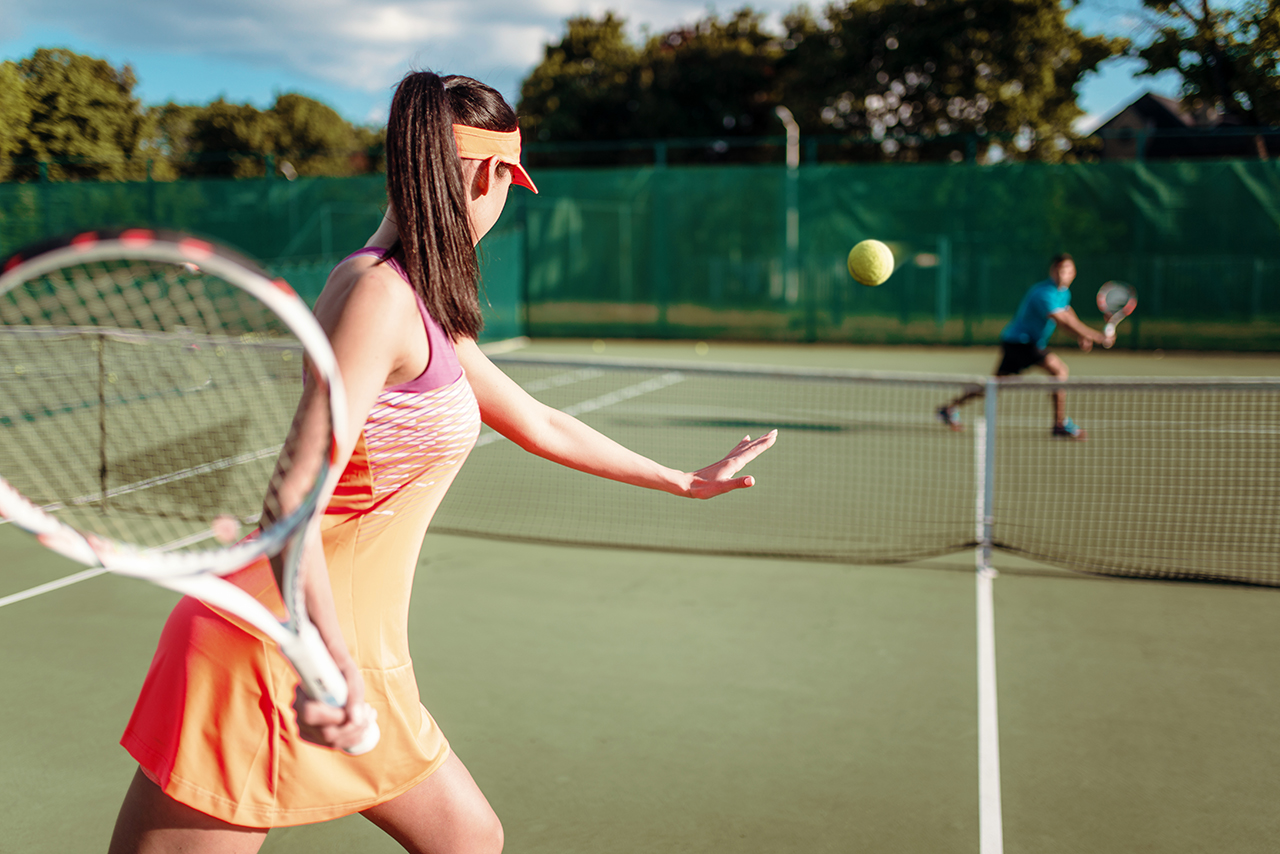 Couple playing tennis on outdoor court